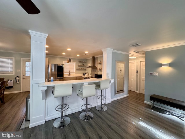 kitchen featuring stainless steel refrigerator, white cabinetry, kitchen peninsula, dark hardwood / wood-style floors, and a kitchen bar