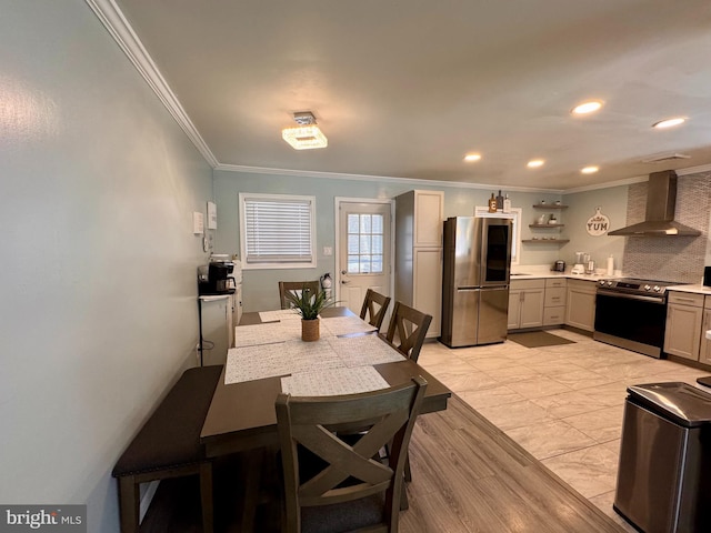 kitchen with crown molding, backsplash, appliances with stainless steel finishes, wall chimney exhaust hood, and light hardwood / wood-style flooring