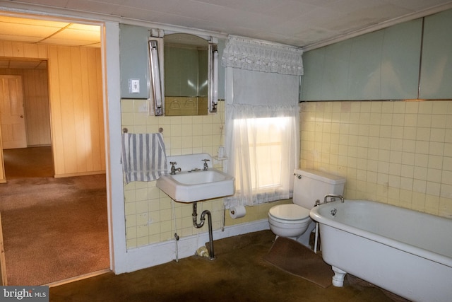 bathroom featuring a tub to relax in, sink, tile walls, and toilet