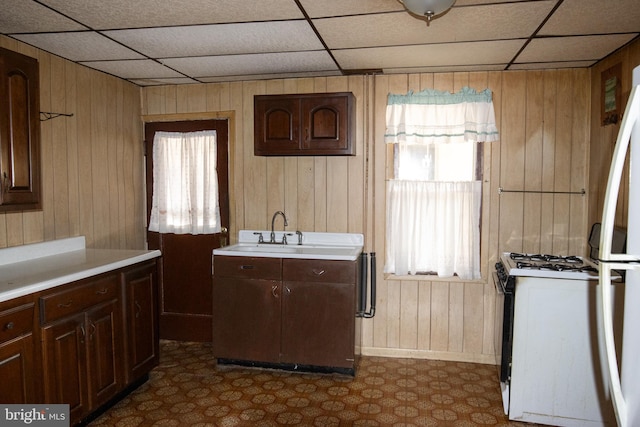 kitchen with white appliances, wooden walls, and sink