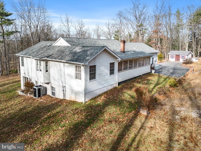 exterior space with a sunroom, central AC unit, and a lawn