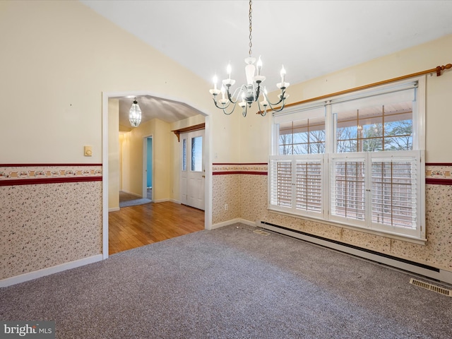 spare room featuring hardwood / wood-style flooring, an inviting chandelier, lofted ceiling, and a baseboard heating unit