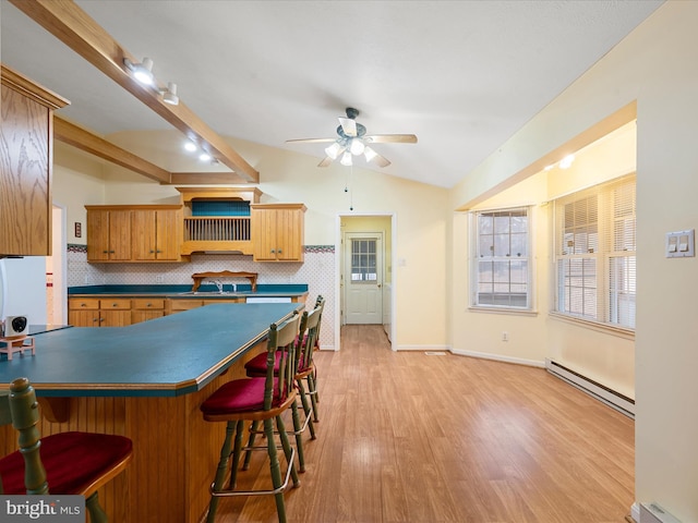 kitchen with lofted ceiling, a baseboard heating unit, ceiling fan, light wood-type flooring, and tasteful backsplash