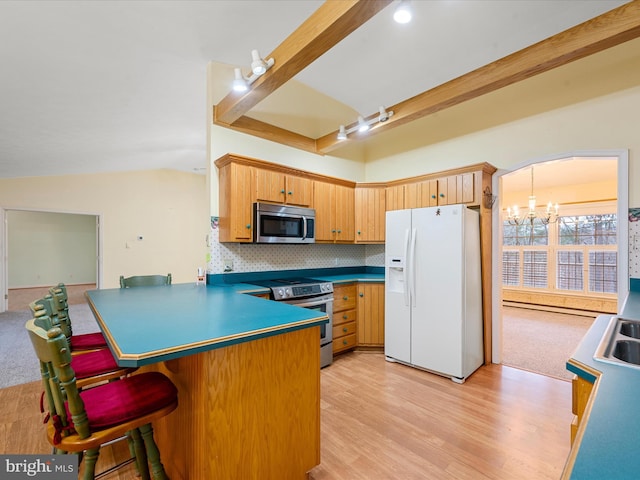 kitchen featuring tasteful backsplash, stainless steel appliances, vaulted ceiling, an inviting chandelier, and light hardwood / wood-style floors