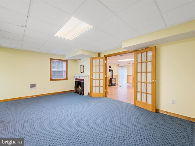 basement featuring carpet, french doors, and a drop ceiling