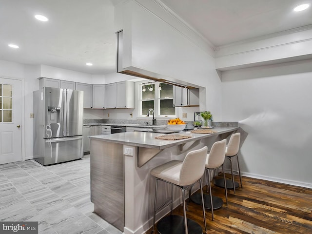 kitchen with stainless steel appliances, light hardwood / wood-style floors, kitchen peninsula, gray cabinets, and crown molding