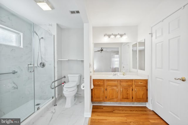 bathroom with ceiling fan, wood-type flooring, toilet, vanity, and a shower with shower door