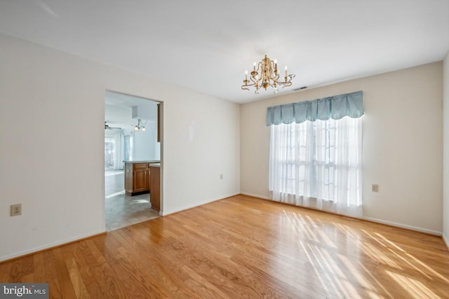 spare room with light hardwood / wood-style flooring and a notable chandelier