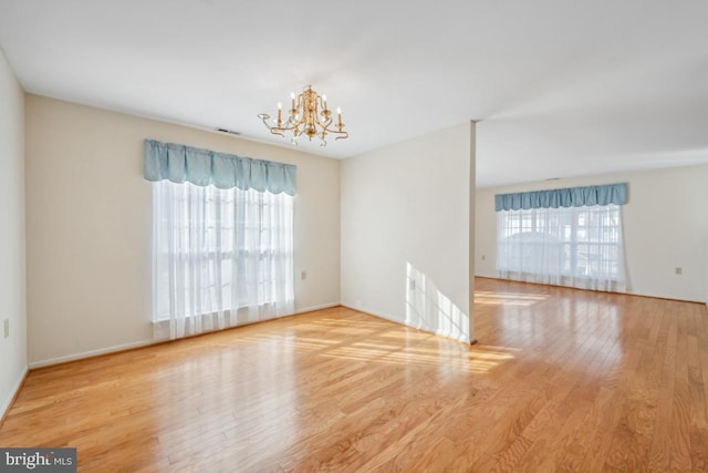 unfurnished room with a notable chandelier and hardwood / wood-style flooring