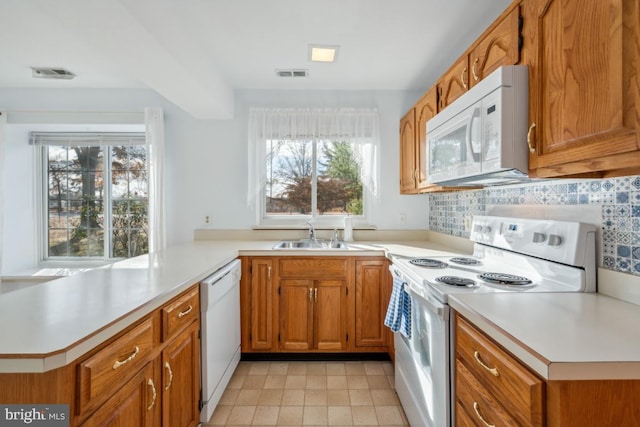 kitchen featuring kitchen peninsula, decorative backsplash, white appliances, and sink