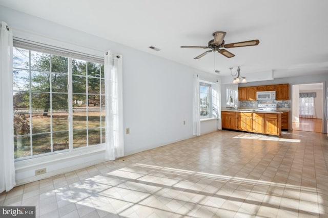 kitchen with backsplash, ceiling fan, plenty of natural light, and white appliances