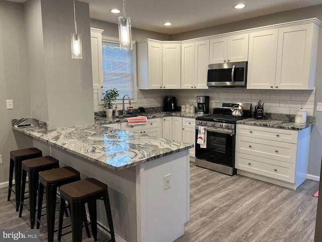 kitchen featuring white cabinets, kitchen peninsula, decorative backsplash, and stainless steel appliances