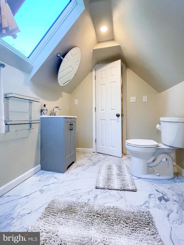 bathroom with vanity, toilet, and vaulted ceiling with skylight