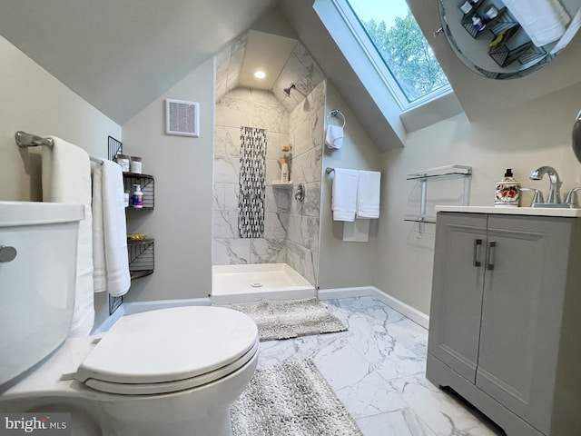 bathroom with toilet, vaulted ceiling with skylight, vanity, and a tile shower