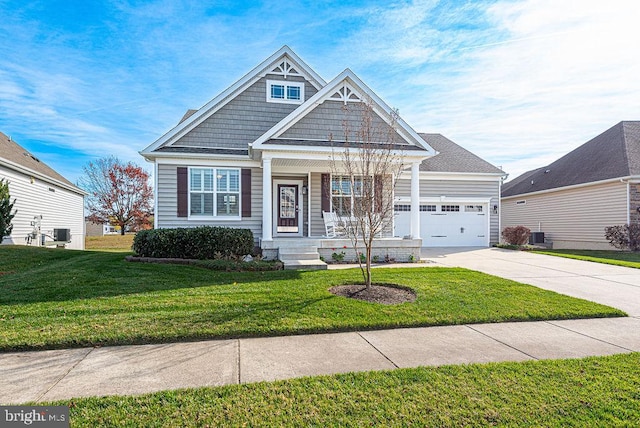 craftsman-style house with covered porch, cooling unit, a garage, and a front yard