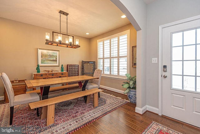 dining space with a notable chandelier, plenty of natural light, and dark hardwood / wood-style flooring