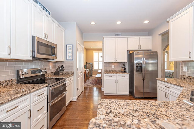 kitchen with light stone counters, white cabinetry, dark wood-type flooring, and appliances with stainless steel finishes