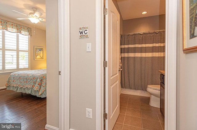 bathroom with ceiling fan, walk in shower, wood-type flooring, toilet, and vanity