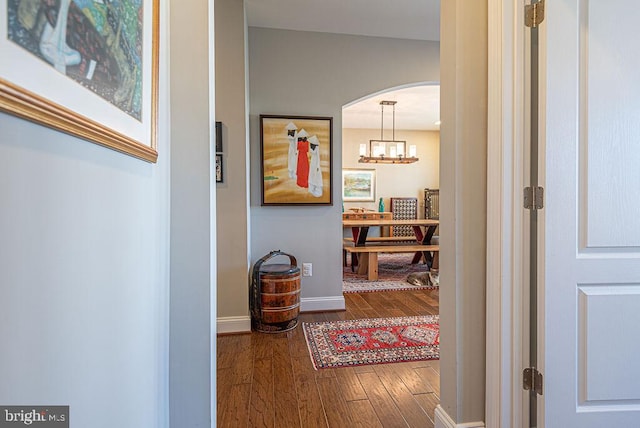 hall with dark hardwood / wood-style flooring and a notable chandelier