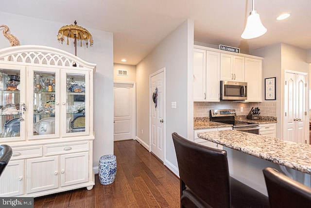 kitchen with pendant lighting, dark hardwood / wood-style floors, decorative backsplash, white cabinetry, and stainless steel appliances