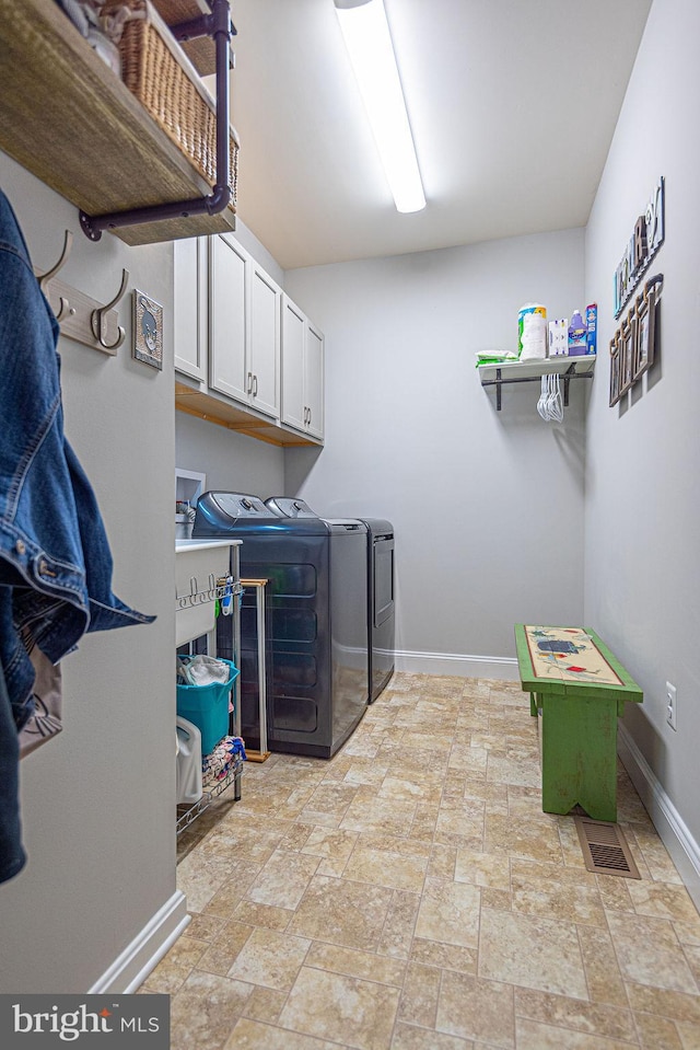 clothes washing area with cabinets and separate washer and dryer