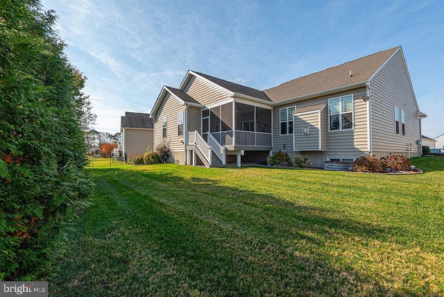 rear view of property featuring a lawn and a sunroom