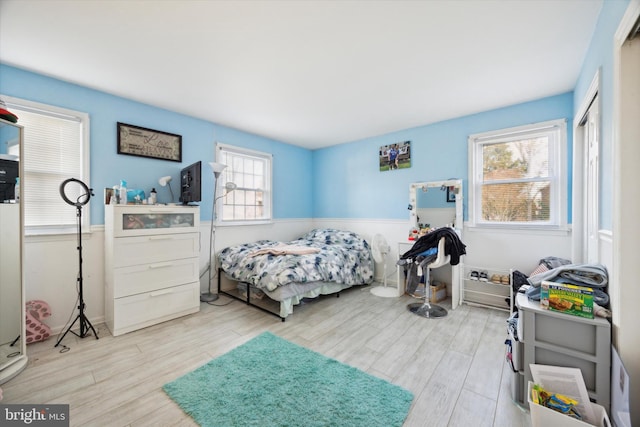 bedroom with multiple windows and light hardwood / wood-style flooring