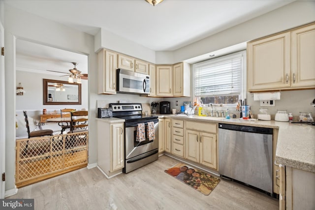 kitchen featuring light wood-type flooring, appliances with stainless steel finishes, and cream cabinetry