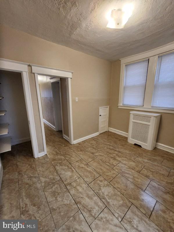 interior space with radiator heating unit, a textured ceiling, and a closet