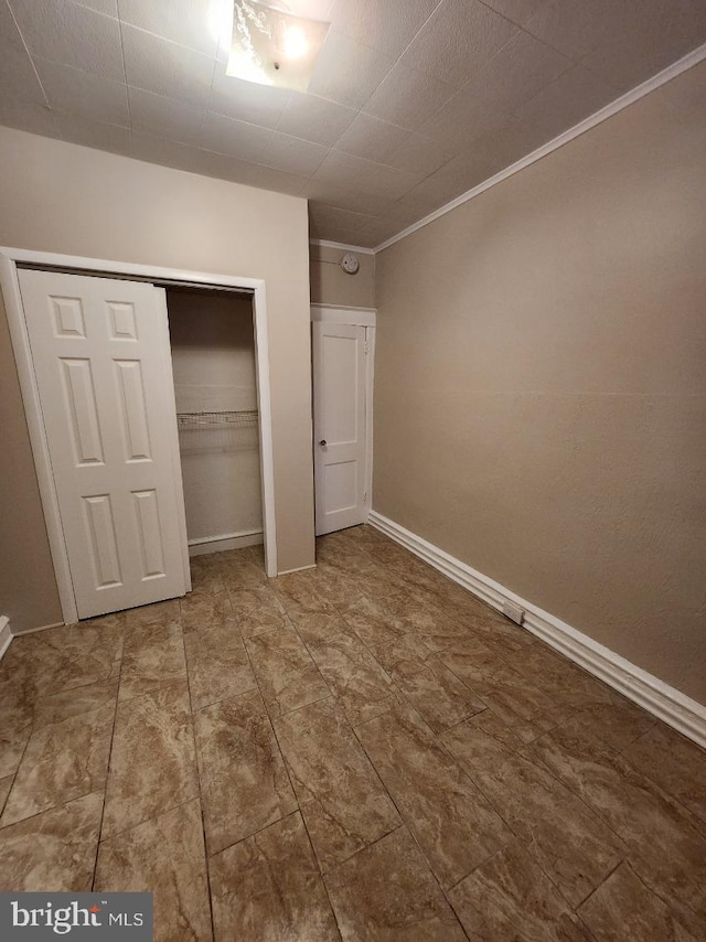 unfurnished bedroom featuring crown molding and a closet