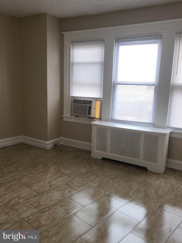 tiled empty room featuring radiator, cooling unit, and a textured ceiling