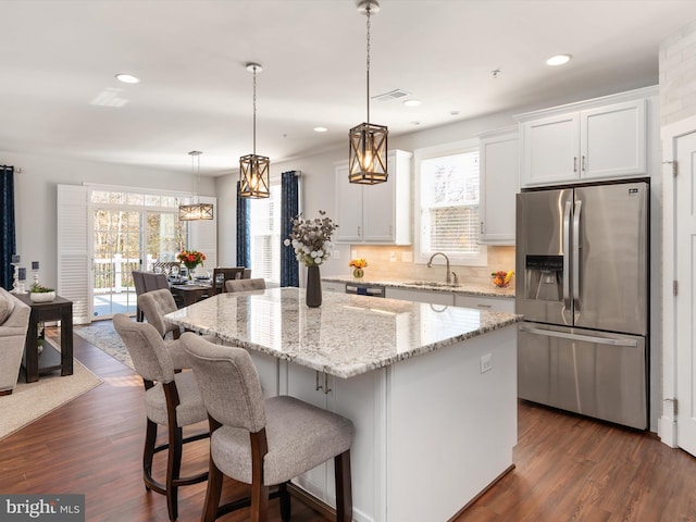 kitchen with stainless steel fridge, white cabinetry, dark hardwood / wood-style flooring, and a center island