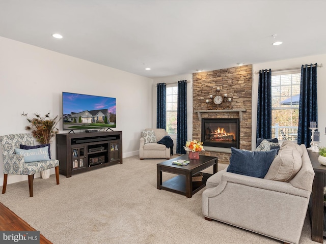 living room featuring a wealth of natural light, a stone fireplace, and light carpet