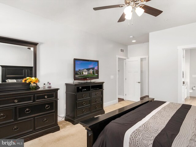 bedroom featuring ensuite bathroom, light carpet, and ceiling fan