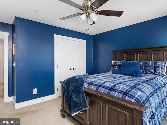 bedroom featuring light carpet, ceiling fan, and a closet