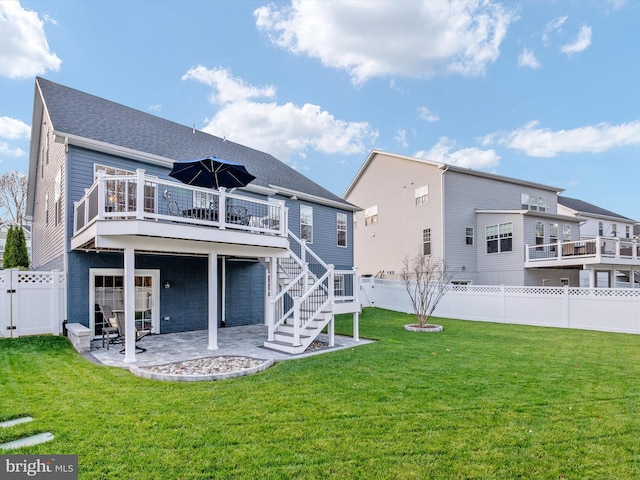 rear view of house with a wooden deck, a patio, and a yard