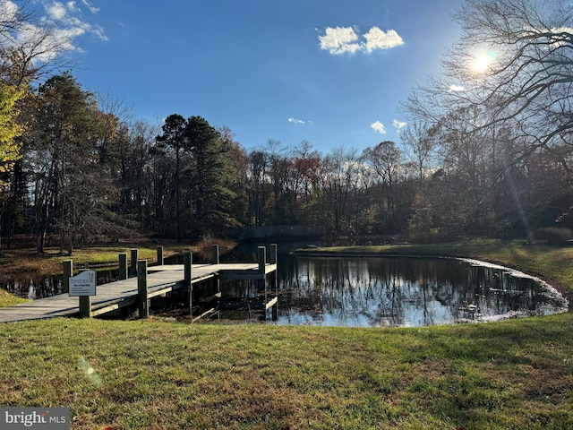 view of dock with a lawn and a water view