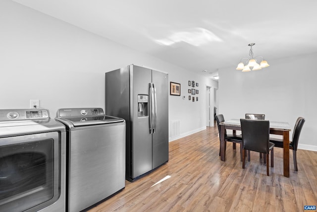 washroom with light hardwood / wood-style floors, washing machine and dryer, and a notable chandelier