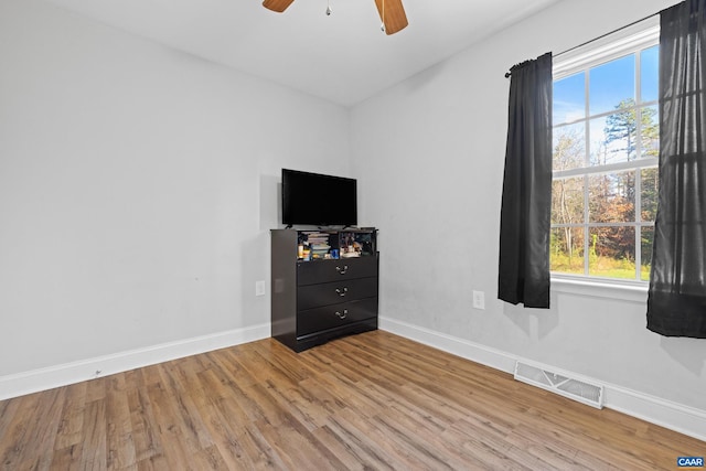 unfurnished bedroom featuring light wood-type flooring, multiple windows, ceiling fan, and vaulted ceiling