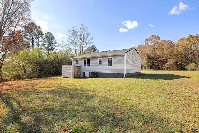 rear view of house with central air condition unit and a lawn