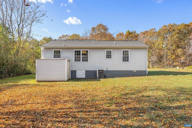 rear view of house featuring central AC unit and a yard