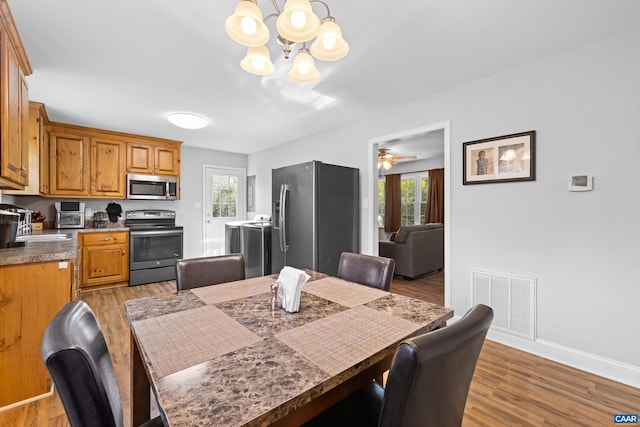 dining area featuring light hardwood / wood-style floors, ceiling fan with notable chandelier, and plenty of natural light