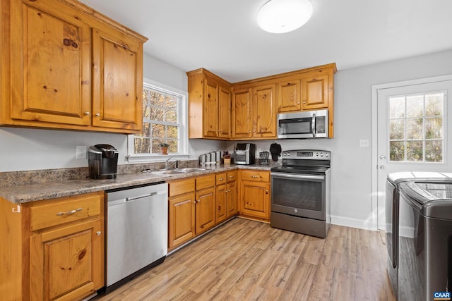 kitchen featuring appliances with stainless steel finishes, a healthy amount of sunlight, sink, and washer and clothes dryer