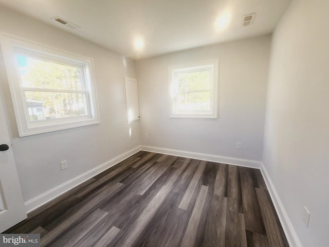 spare room with plenty of natural light and dark hardwood / wood-style floors