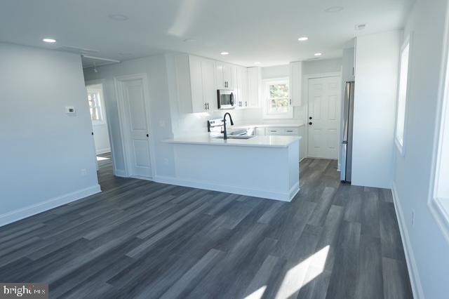 122 Roselawn Rd, Annapolis, MD 21403 - kitchen with appliances with stainless steel finishes, a peninsula, white cabinetry, dark wood-type flooring, and light countertops