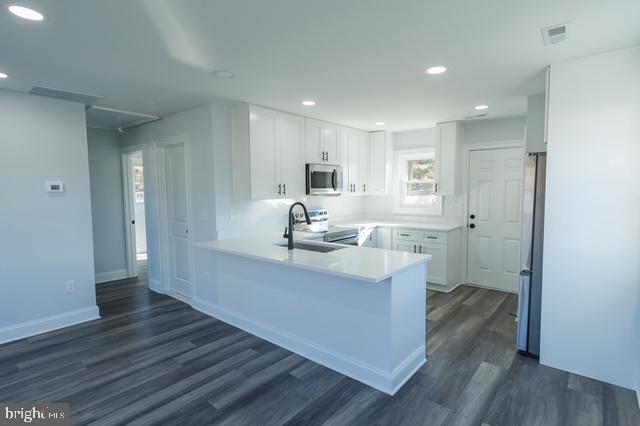 122 Roselawn Rd, Annapolis, MD 21403 - kitchen with appliances with stainless steel finishes, a peninsula, dark wood finished floors, white cabinetry, and recessed lighting