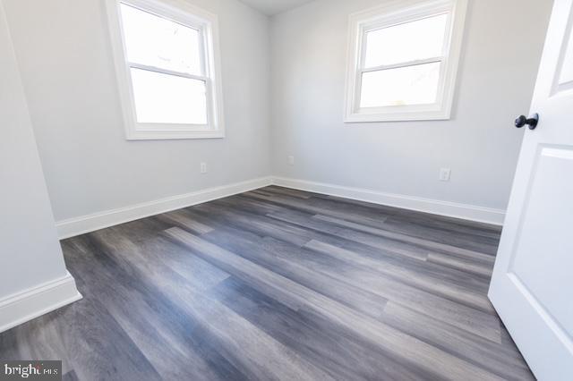 unfurnished room with dark wood-type flooring