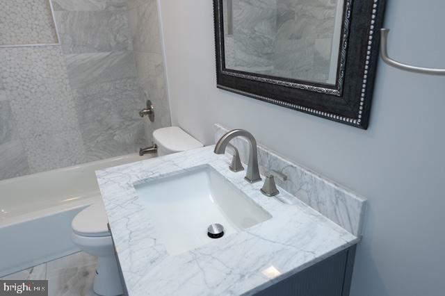 full bathroom featuring vanity, toilet, and tiled shower / bath combo