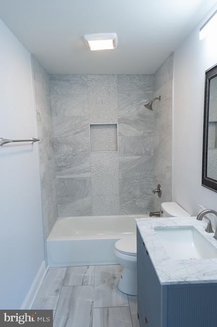 full bathroom featuring vanity, tiled shower / bath combo, and toilet