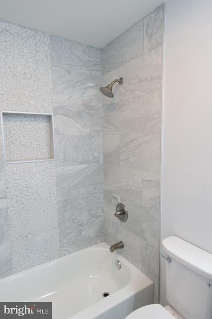 bathroom with toilet and tiled shower / bath